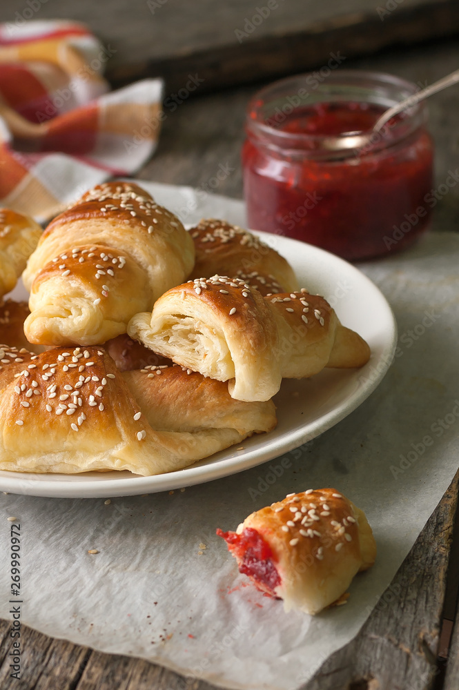 Homemade croissants with berry jam on wooden background
