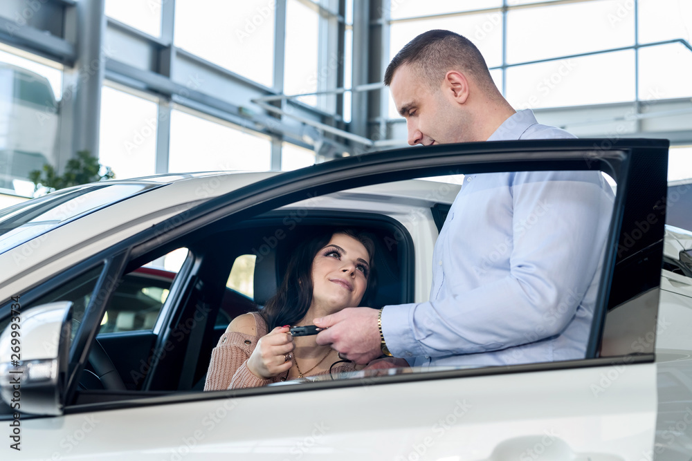 Dealer giving keys from new car to beautiful woman Dealer giving keys from new car to beautiful woman