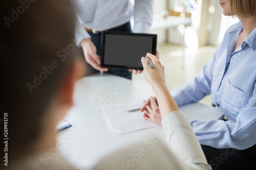 business, people and technology concept - close up of businessman showing tablet computer to colleagues at office