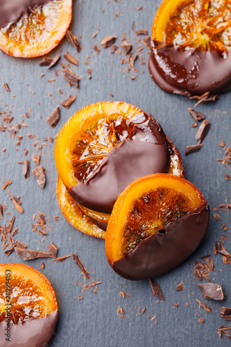 Candied orange slices in chocolate. Slate background. Top view.