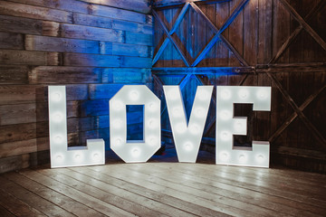 Wooden glowing love text letters. Rustic wedding dance floor lamp.
