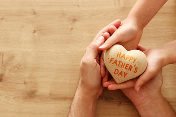 father and little child holding together wooden heart. Happy father's day concept.