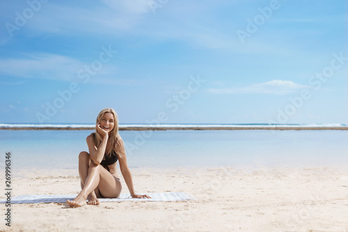 So warm nice and relaxing. Enthusiastic attractive blond woman wearing bikini sit alone beach blanket touch sand laughing happily enjoy sunbathing summer vacation, tropical island holiday