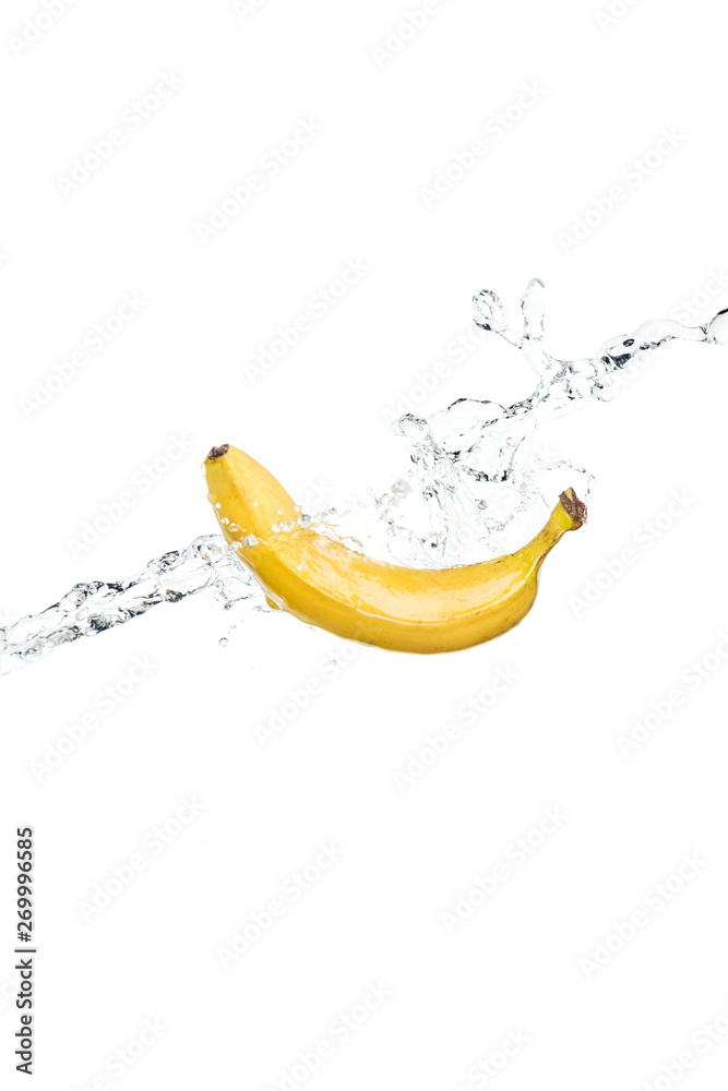 whole ripe yellow banana and water splash isolated on white