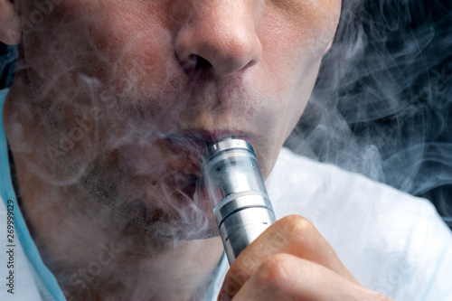 Close-up - young man vaping e-cigarette