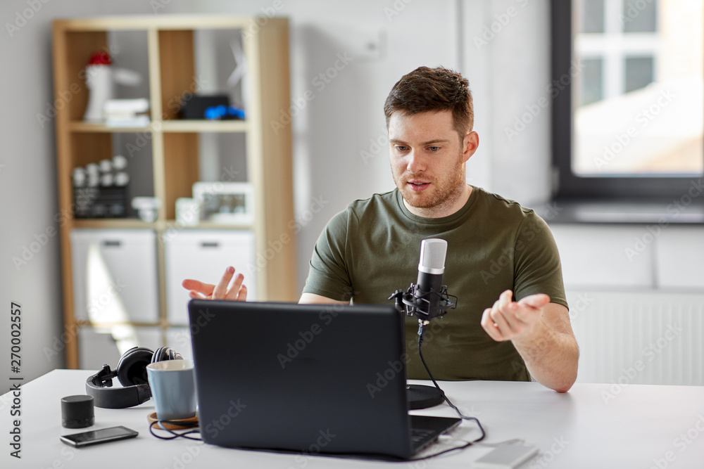 technology, mass media and podcast concept - happy young male audio blogger with laptop computer and microphone broadcasting at home office technology, mass media and podcast concept - happy young male audio blogger with laptop computer and microphone broadcasting at home office