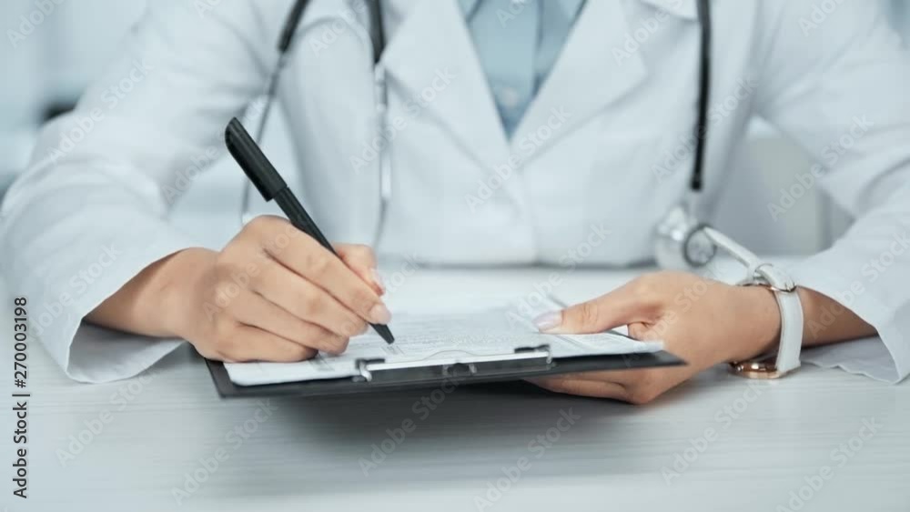cropped view of doctor writing on clipboard at workplace cropped view of doctor writing on clipboard at workplace