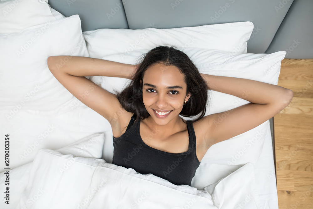 Young beautiful happy woman waking up on bed, top view Young beautiful happy woman waking up on bed, top view