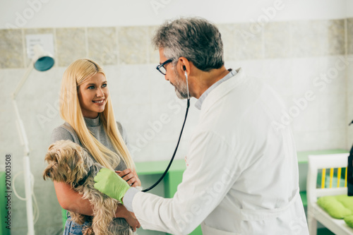 Fototapeta Naklejka Na Ścianę i Meble -  woman holding her dog while veterinarian examine it