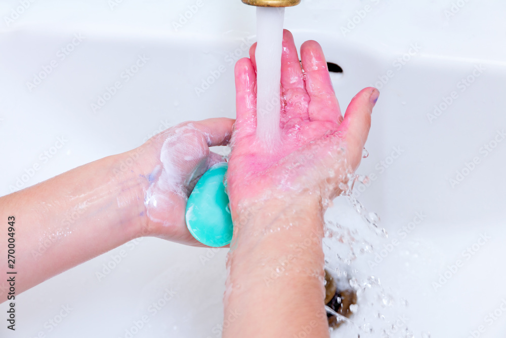 Fototapeta premium girl washes her hands in paint after drawing