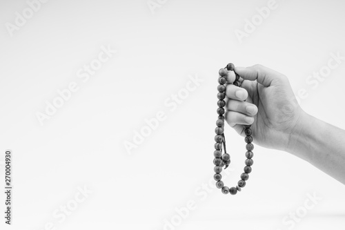 Hand holding a muslim rosary beads or Tasbih on black and white. Copy space and selective focus photo