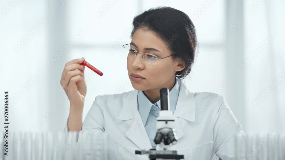 selective focus of african american scientist in glasses looking at blood sample in test tube in lab selective focus of african american scientist in glasses looking at blood sample in test tube in lab