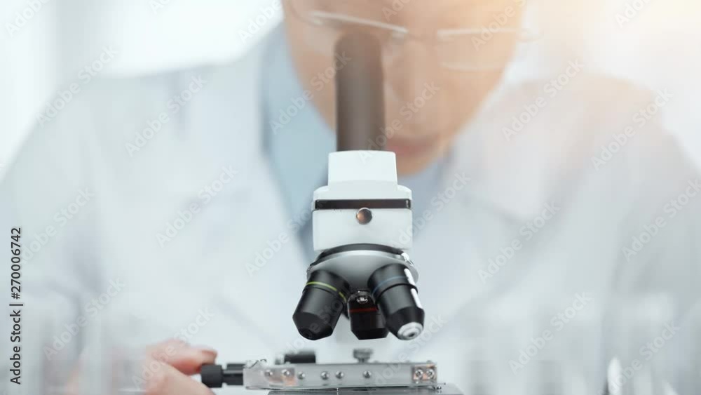 selective focus of african american scientist in glasses using microscope with back light selective focus of african american scientist in glasses using microscope with back light