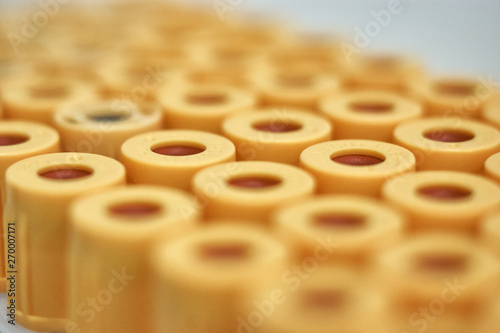 macro of test tubes with yellow top, against a gradient of white background. Selective focus
