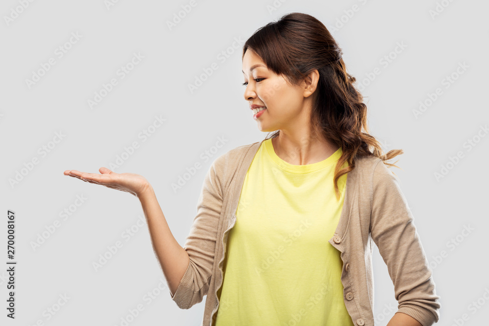 people and advertisement concept - happy asian young woman holding something imaginary on empty hand over pink background people and advertisement concept - happy asian young woman holding something imaginary on empty hand over pink background
