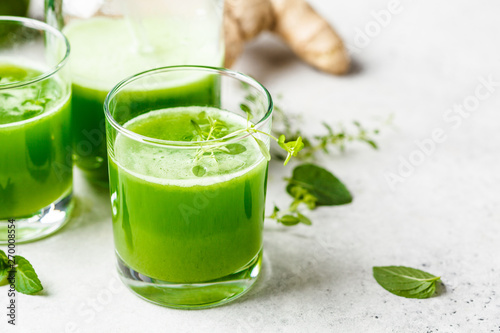 Green detox juice with ginger and mint in glasses and jars. photo