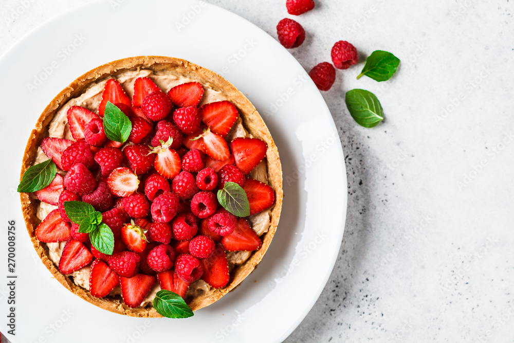 Whole berry tart with raspberries, strawberries and cream on white dish, top view. - obrazy, fototapety, plakaty 