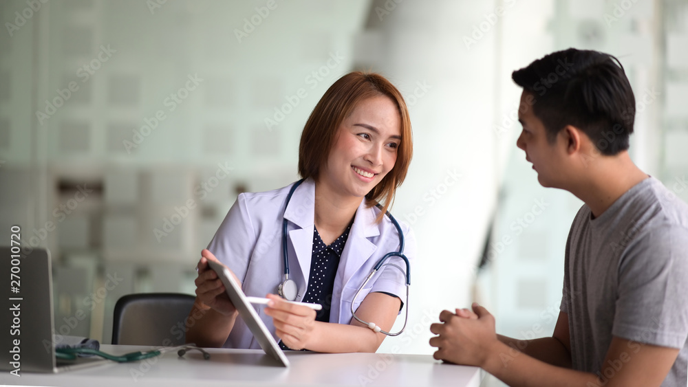 Asian female doctor using tablet computer and talking to male Asian patient Asian female doctor using tablet computer and talking to male Asian patient
