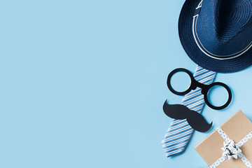 Fathers day concept with hat, glasses and tie on blue background