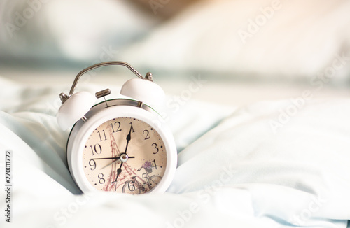 White alarm clock on the bed, have copy space. Concept Notification of various events during 07.00 am.
