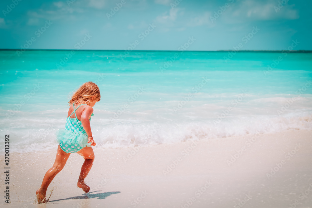 Fototapeta premium happy little girl run play with waves on the beach