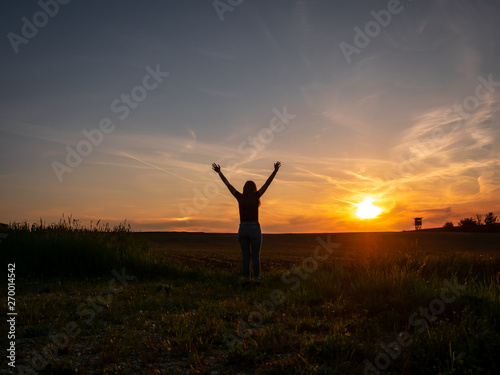 Junge Frau mit erhobenen Händen im Sonnenuntegang, Freieheit, Lebensfreude, Reise