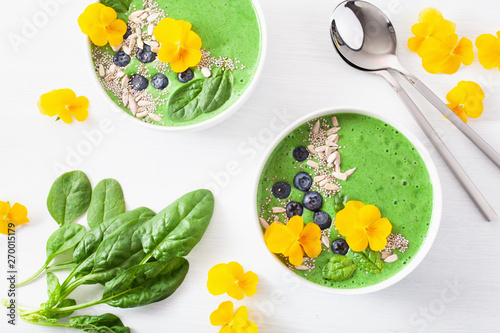 green spinach smoothie bowl with blueberry, chia seed and edible pansy flowers
