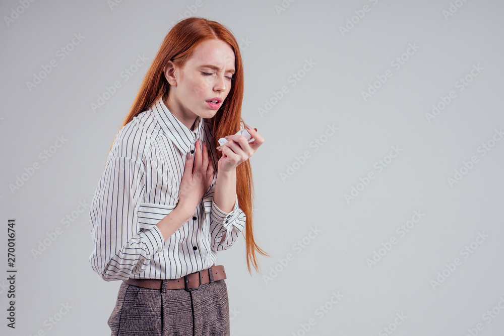 redhead businesswoman tourist student in a striped shirt having asthma using the asthma inhaler for being healthy white background studio redhead businesswoman tourist student in a striped shirt having asthma using the asthma inhaler for being healthy white background studio