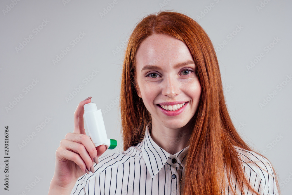 redhead businesswoman tourist student in a striped shirt having asthma using the asthma inhaler for being healthy white background studio redhead businesswoman tourist student in a striped shirt having asthma using the asthma inhaler for being healthy white background studio
