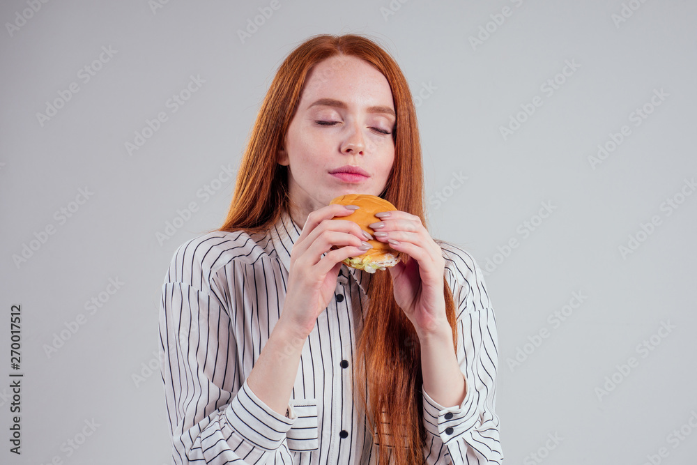 redheared hungry woman in striped shirt eating USA burger visa traveler white background studio redheared hungry woman in striped shirt eating USA burger visa traveler white background studio