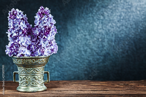 vintage bronze bowl with flowers of lilac on black background with copyspace photo