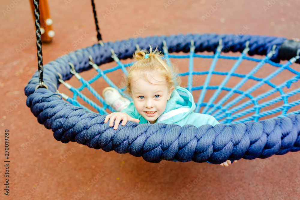 Cute caucasian toddler girl 4 years old having fun on a slide in a playground in the summer day. Cute caucasian toddler girl 4 years old having fun on a slide in a playground in the summer day.