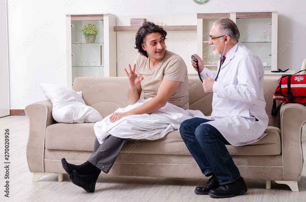 Old male doctor visiting young male patient  