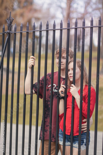 Young people stand by the metallic fence