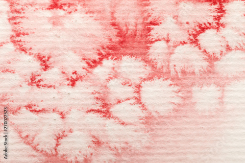 close up view of red watercolor paint spill on textured paper background
