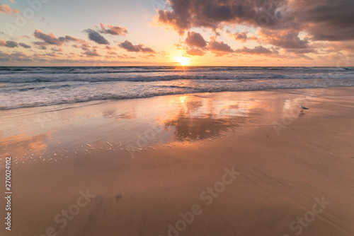 Sunrise at tropical sandy beach with mild waves