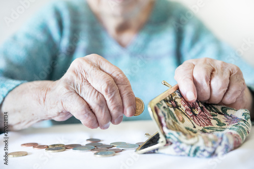 Detailed closeup photo of elderly 96 years old womans hands counting remaining coins from pension in her wallet after paying bills. Unsustainability of social transfers and pension system. photo