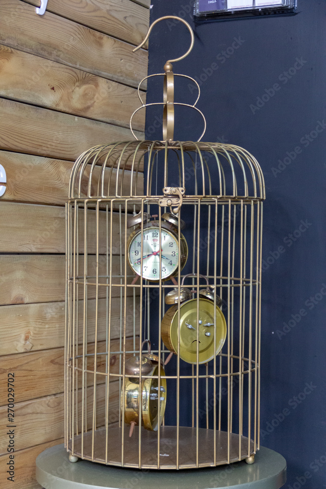 three 3 alarm clocks hanging in a bird cage