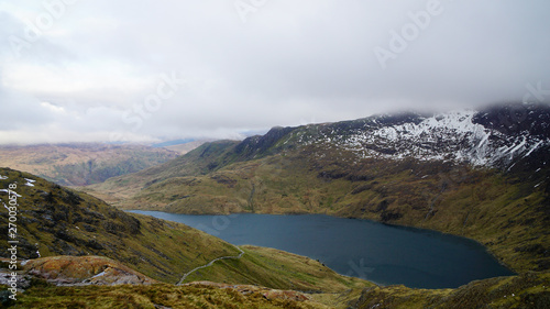 Stunning mountain view with a beautiful lake  foggy sky and some melting snow from the top of the mount     captured during a hike at Snowdon in winter  Snowdonia National Park  Wales  United Kingdom 