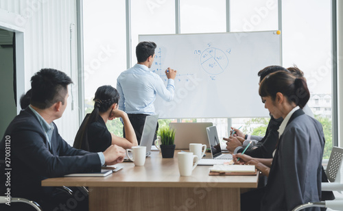 Businessman leader writing on the whiteboard present business marketing graph while meeting with colleagues in office.Business Team Meeting Presentation,Conference Planning Business Concept