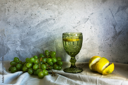 Still life with grapes, lemon and water on the gray background