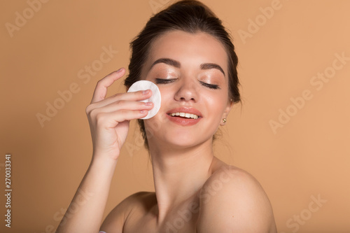 Closeup portrait of young beautiful woman is cleaning her face from makeup with cotton pads. Skin care and beauty concept.