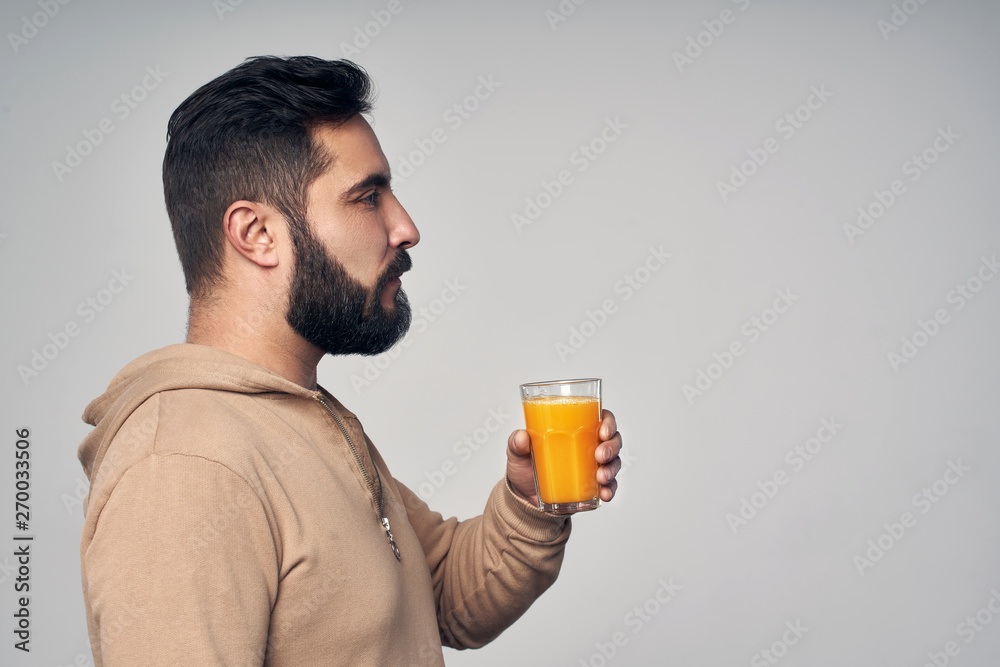 Bearded man holding a glass of orange juice Bearded man holding a glass of orange juice