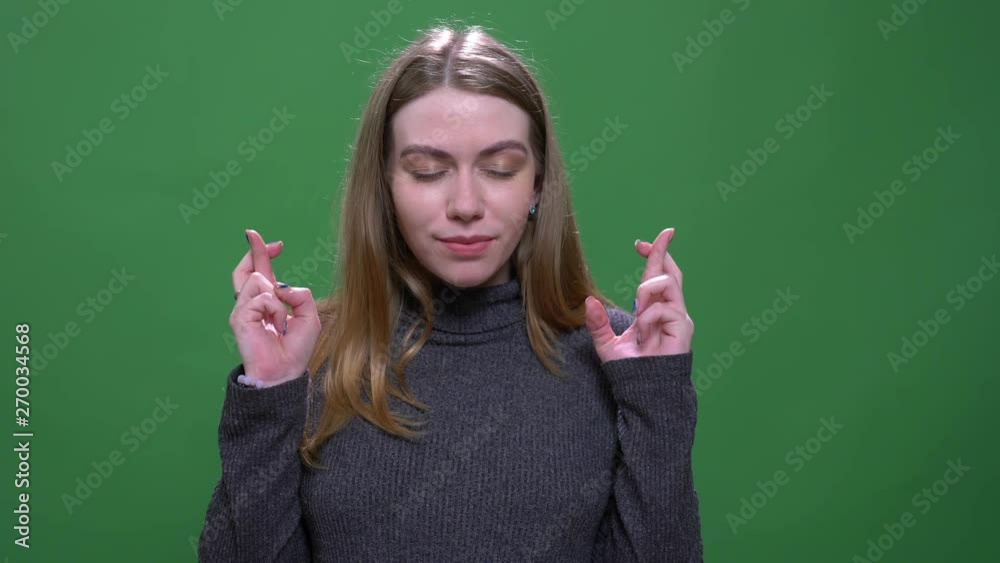 Joyful blonde model prays with crossed fingers hoping for luck and success isolated on green chromakey background. Joyful blonde model prays with crossed fingers hoping for luck and success isolated on green chromakey background.