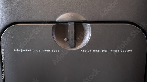 life jacket under your seat, fasten seat belt whilst seated, plane tray table photo