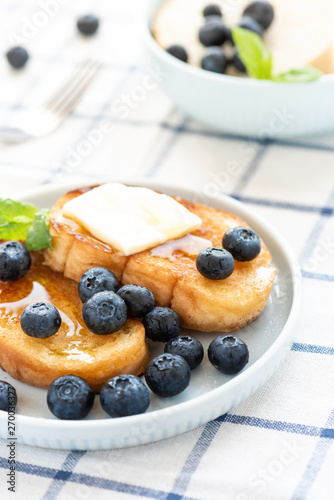 French toast with blueberries, honey and butter on a light plate. Sweet country breakfast.