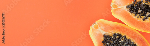 Photography panoramic shot of ripe bright papaya halves with black seeds isolated on orange