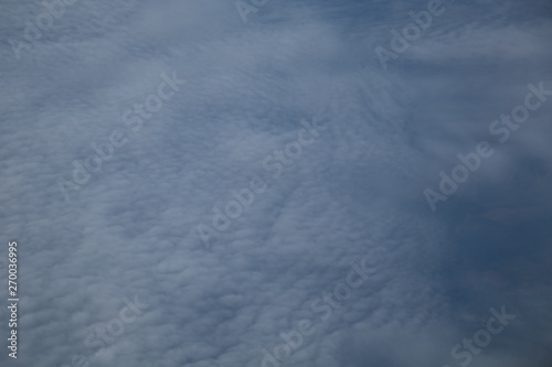 Aerial view from plane window with blue sky and white clouds