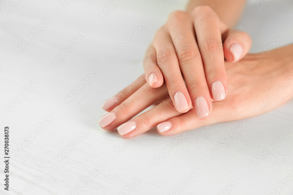 Closeup view of woman with smooth hands and manicure at table, space for text. Spa treatment