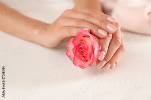 Woman holding flower at table  closeup with space for text. Spa treatment